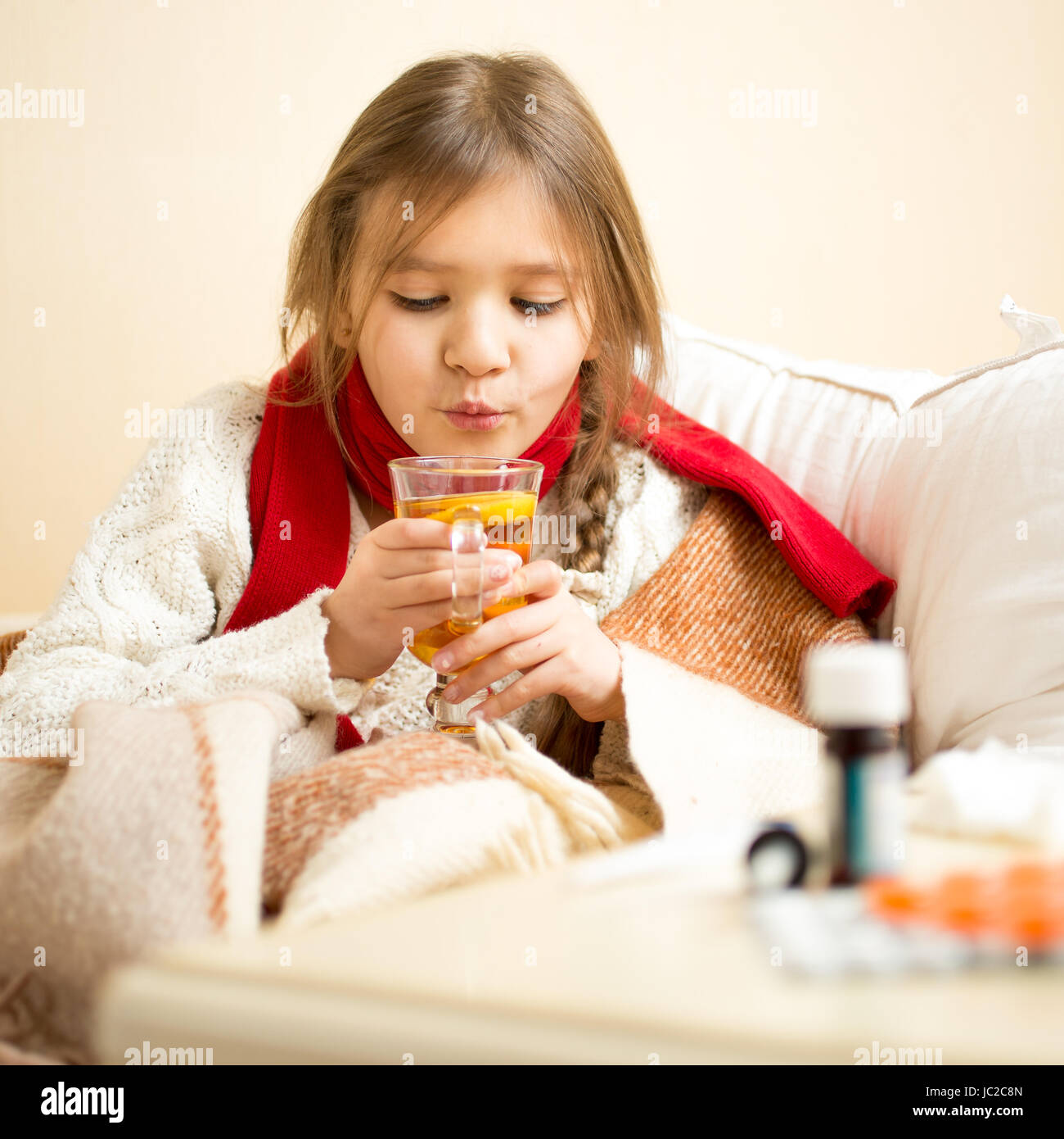 Ritratto di piccoli malati ragazza distesa nel letto e soffiando sul tè caldo Foto Stock