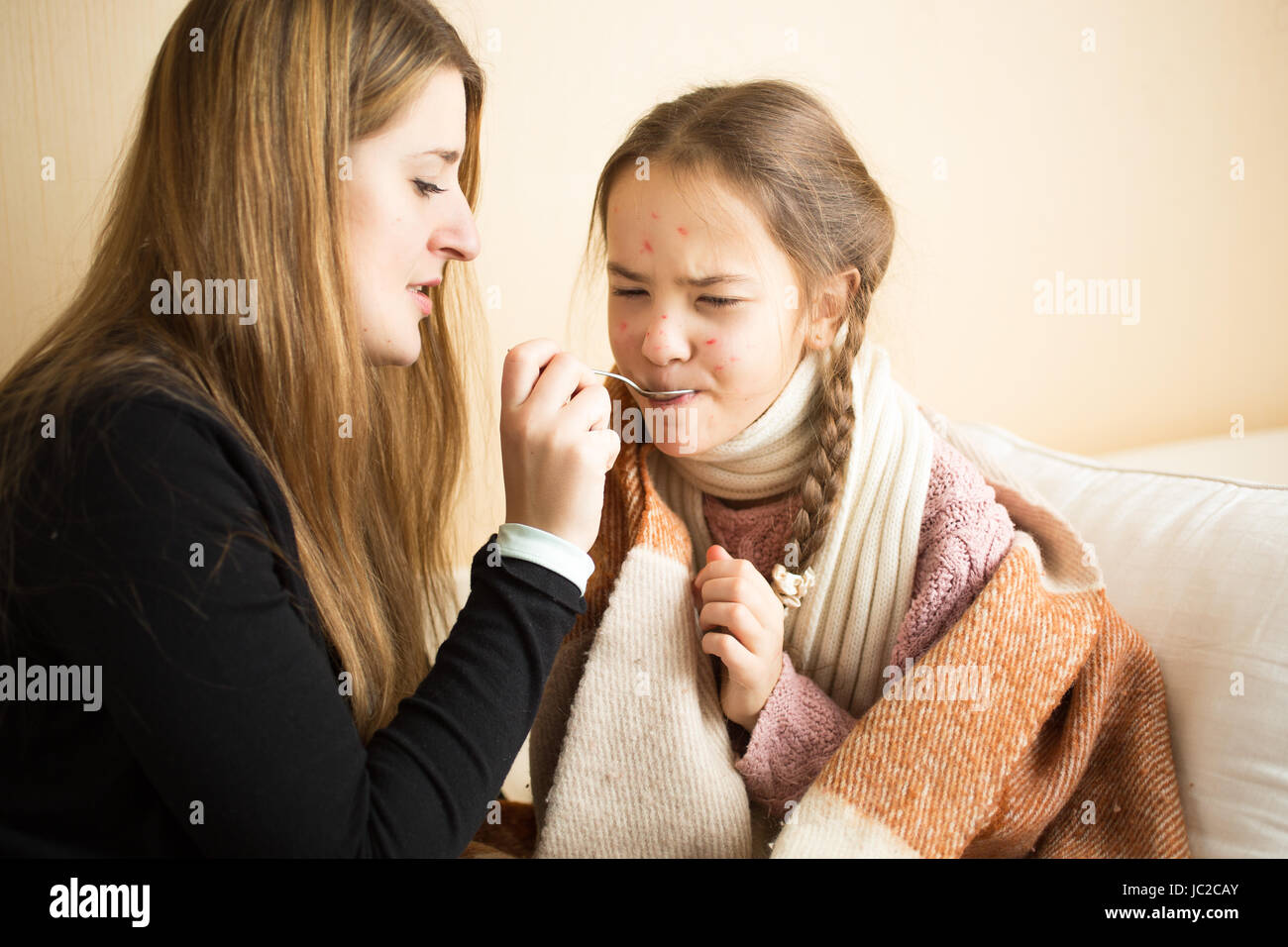 Ritratto di giovane madre figlia dando medicinali sul cucchiaio Foto Stock