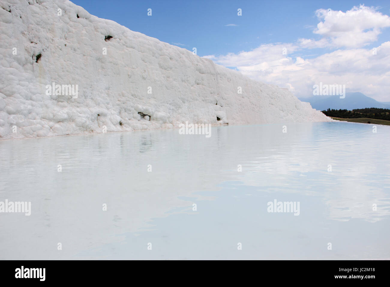 Una vista del travertino dal lato, la più famosa attrazione turistica della Turchia, bianco depositi di calcio sullo sfondo del cielo blu Foto Stock