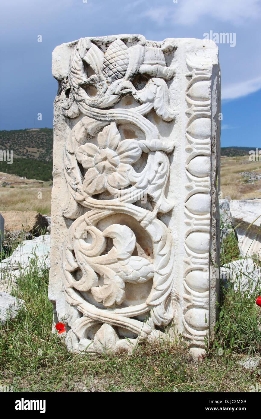 Un pezzo di musica classica greco antico scolpite in bassorilievo pattern, pietre e marmo bianco su uno sfondo di erba verde, fioritura papaveri rossi, blu cielo Foto Stock