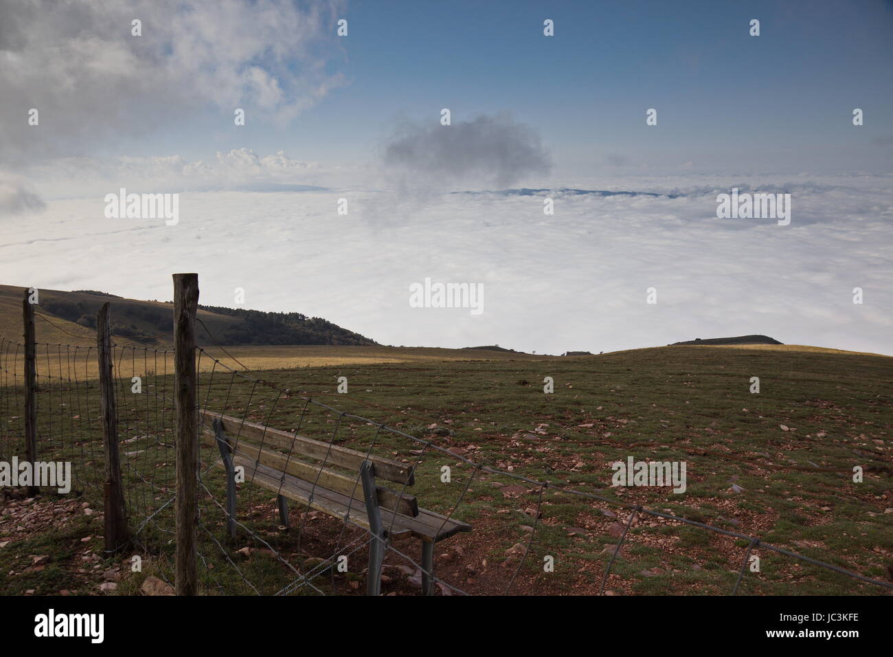 Un banco di seduta sulla cima di una montagna di fronte a un mare di nebbia nella valle sottostante Foto Stock