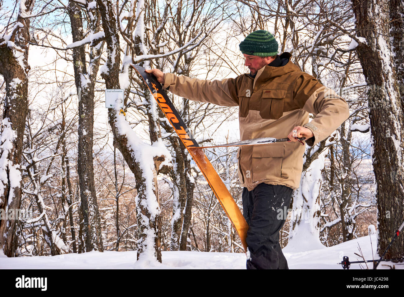 Un uomo prendendo le pelli fuori il suo splitboard nel Vermont backcountry. Foto Stock