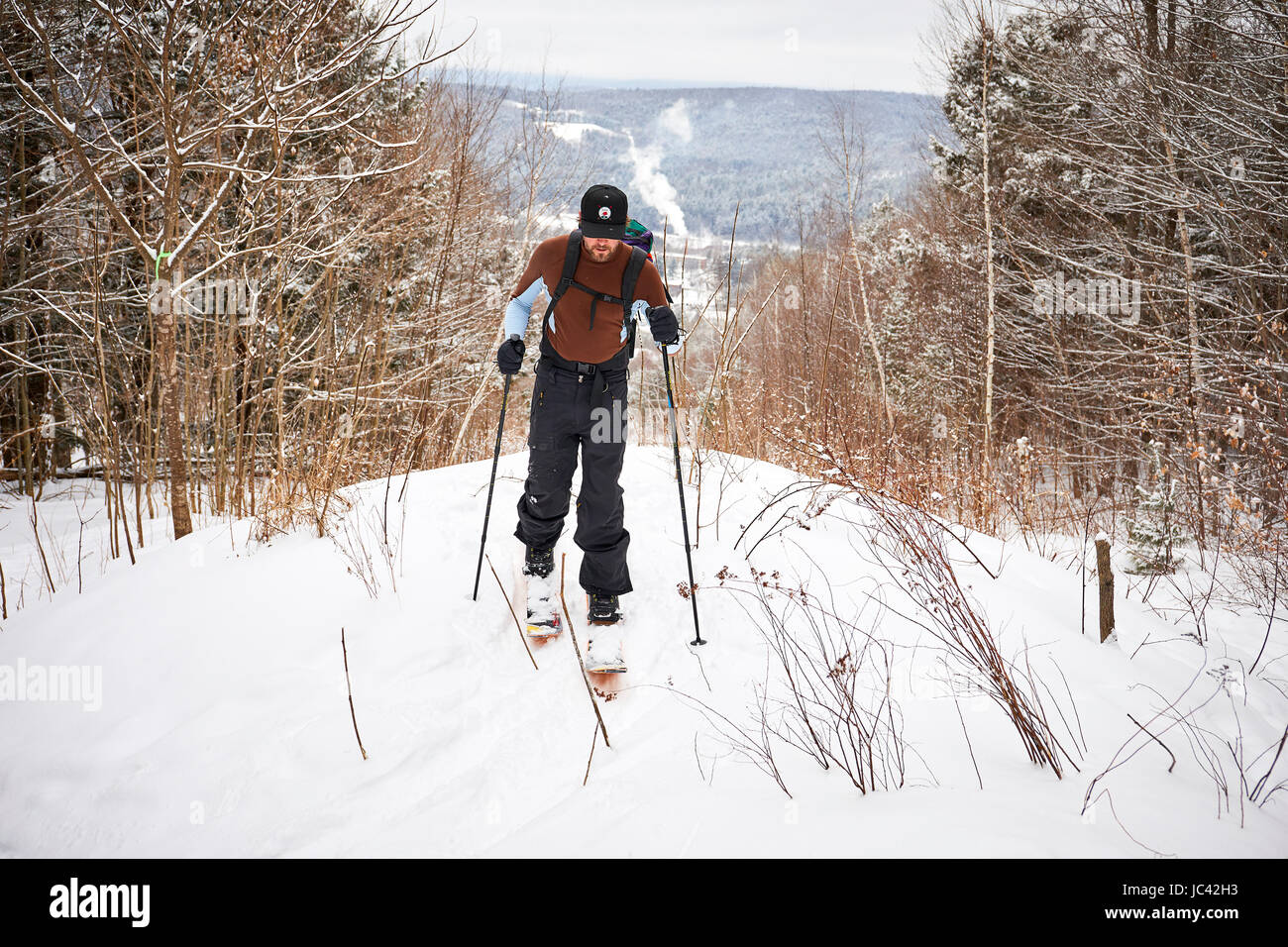 Un uomo la scuoiatura il suo modo attraverso il Vermont backcountry su splitboard. Foto Stock