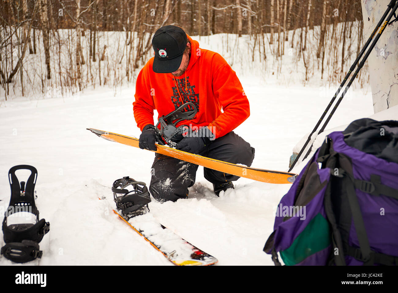 Un uomo prendendo le pelli fuori il suo splitboard nel Vermont backcountry. Foto Stock