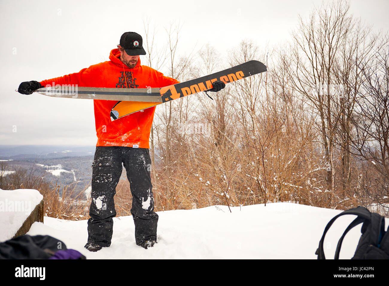 Un uomo prendendo le pelli fuori il suo splitboard nel Vermont backcountry. Foto Stock
