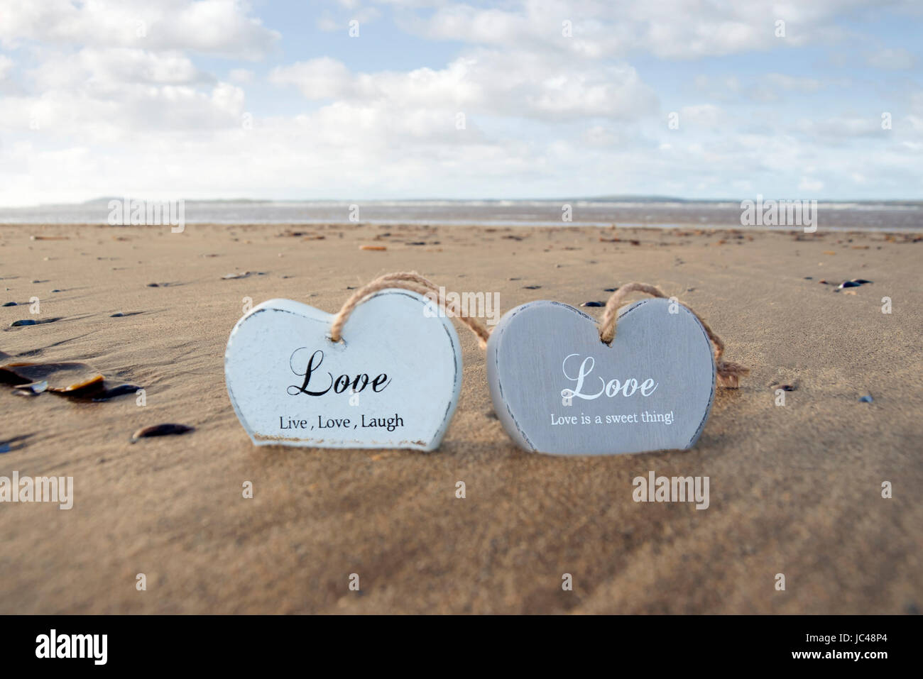 Due inscritto amore in legno cuori di sabbia su una wild Atlantic modo spiaggia irlandese in estate Foto Stock