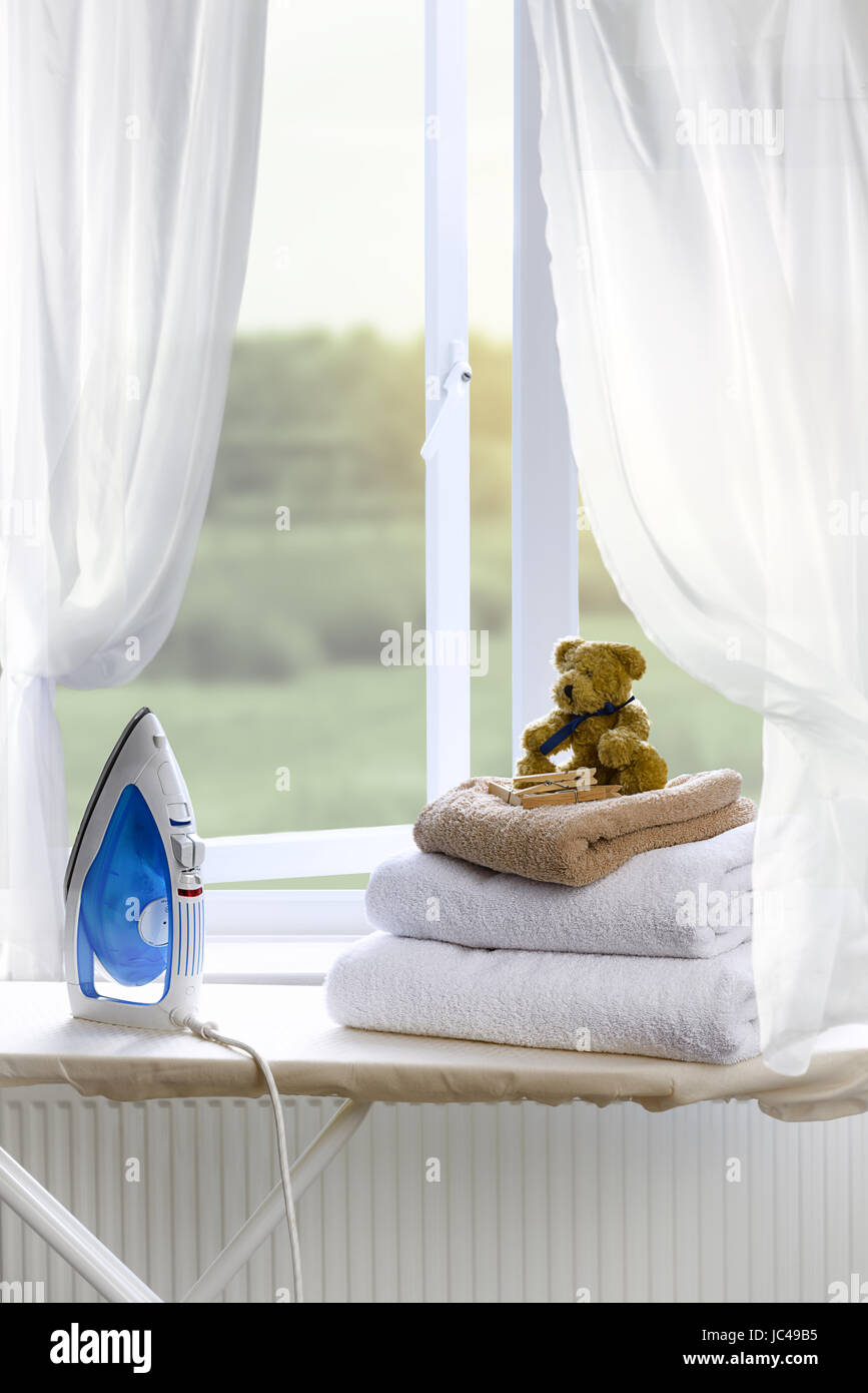 Fresca di bucato asciugamani con ferro accanto a una finestra aperta Foto Stock
