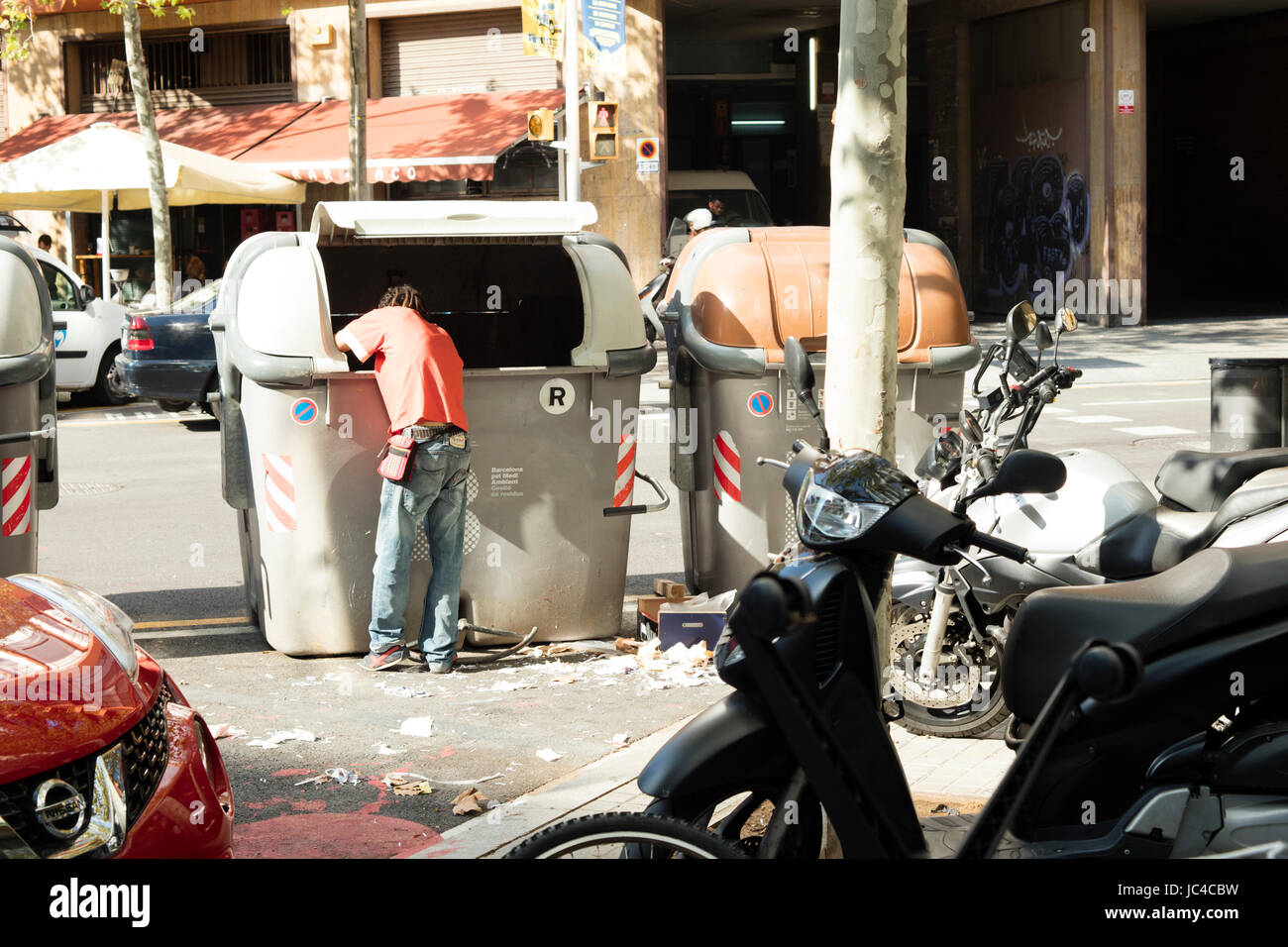 Barcellona, Spagna - 7 Ottobre 2016: senzatetto in cerca di oggetti di valore in un contenitore di rifiuti in Barcellona. Foto Stock