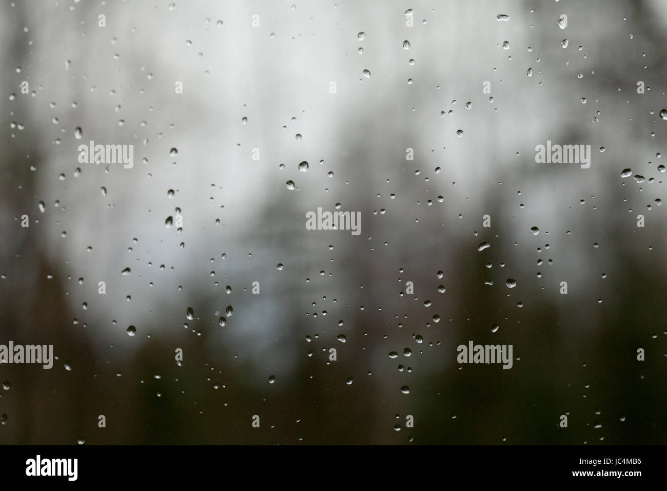 Gocce di pioggia sulla finestra contro un bello sfondo sfocato. Abstract, texture, sfondo. Foto Stock