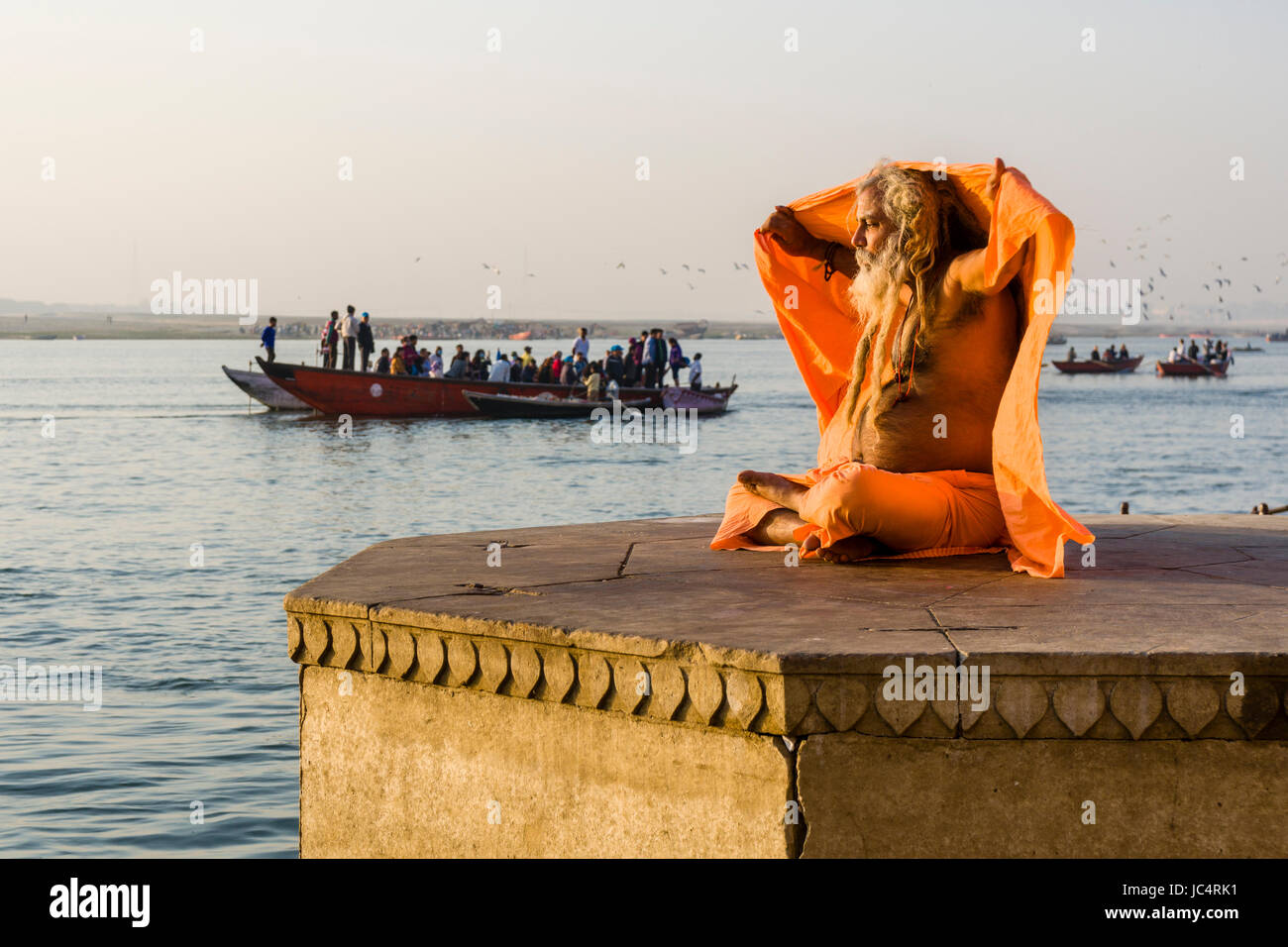Un sadhu, uomo santo, è seduto su una piattaforma presso il fiume sacro Gange a dashashwamedh ghat, principale ghat, nel sobborgo godowlia Foto Stock