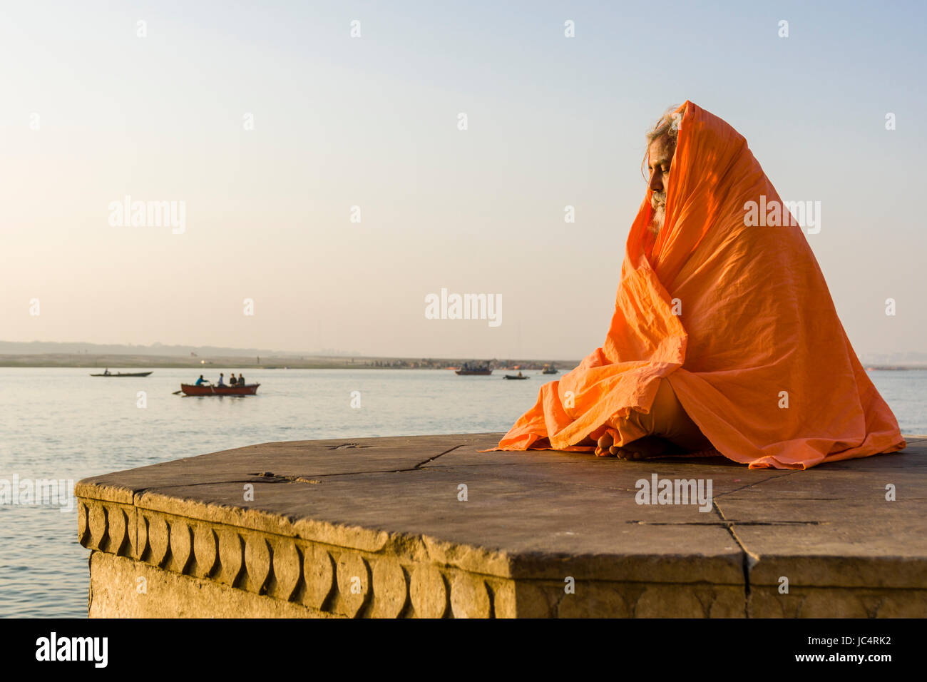 Un sadhu, uomo santo, è seduto e meditando su una piattaforma presso il fiume sacro Gange a dashashwamedh ghat, principale ghat, nel sobborgo godowlia Foto Stock