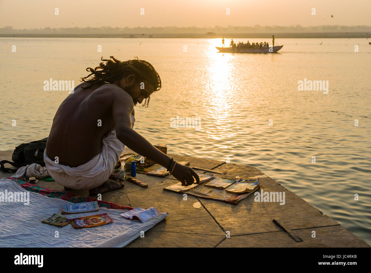 Un sadhu, uomo santo, si sta preparando per un rituale religioso su una piattaforma presso il fiume sacro Gange a meer ghat nel sobborgo godowlia Foto Stock