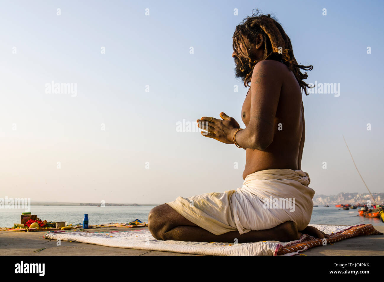 Un sadhu, uomo santo, è seduto e pregando su una piattaforma presso il fiume sacro Gange a meer ghat nel sobborgo godowlia Foto Stock