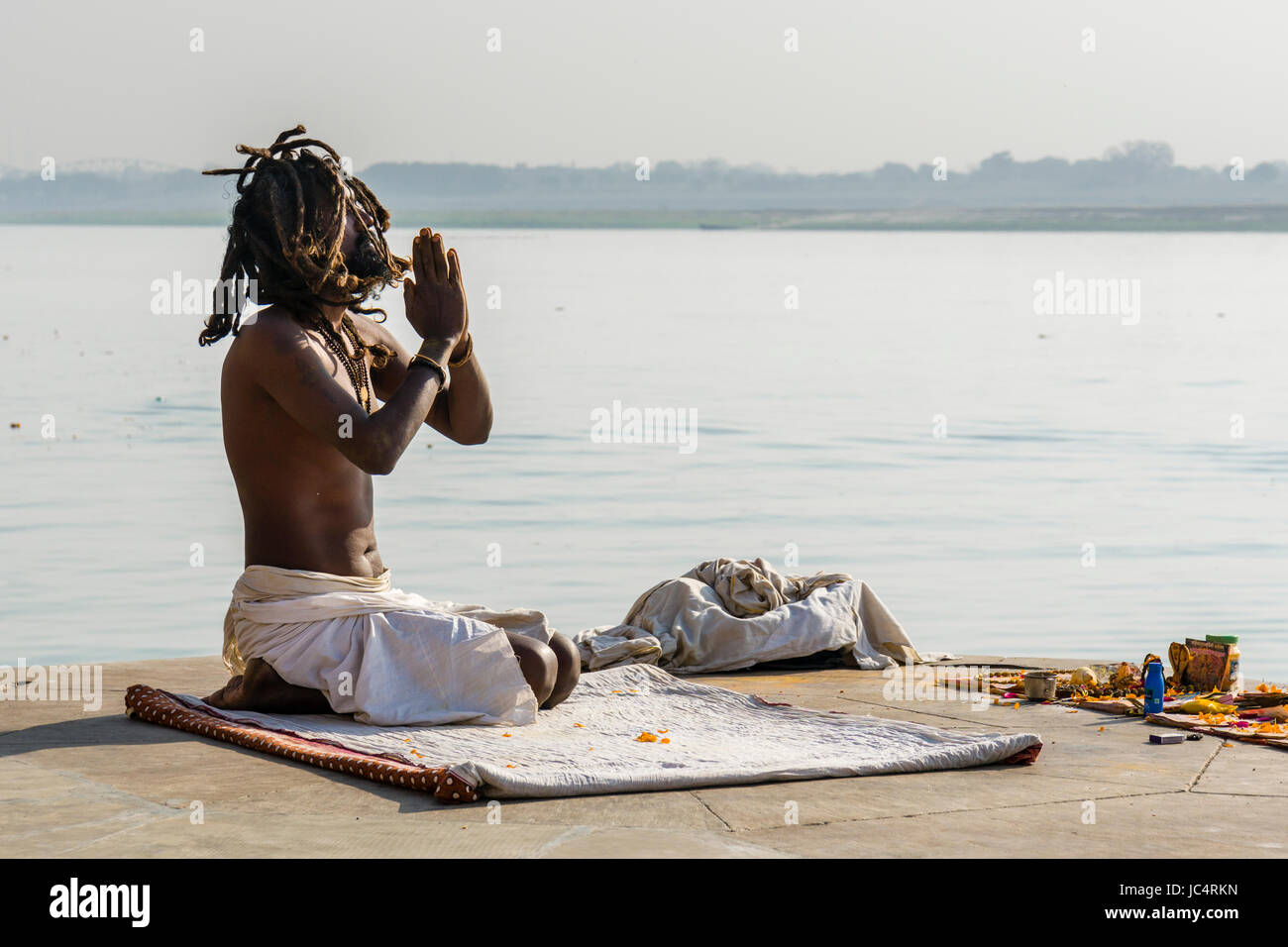 Un sadhu, uomo santo, è seduto e pregando su una piattaforma presso il fiume sacro Gange a meer ghat nel sobborgo godowlia Foto Stock