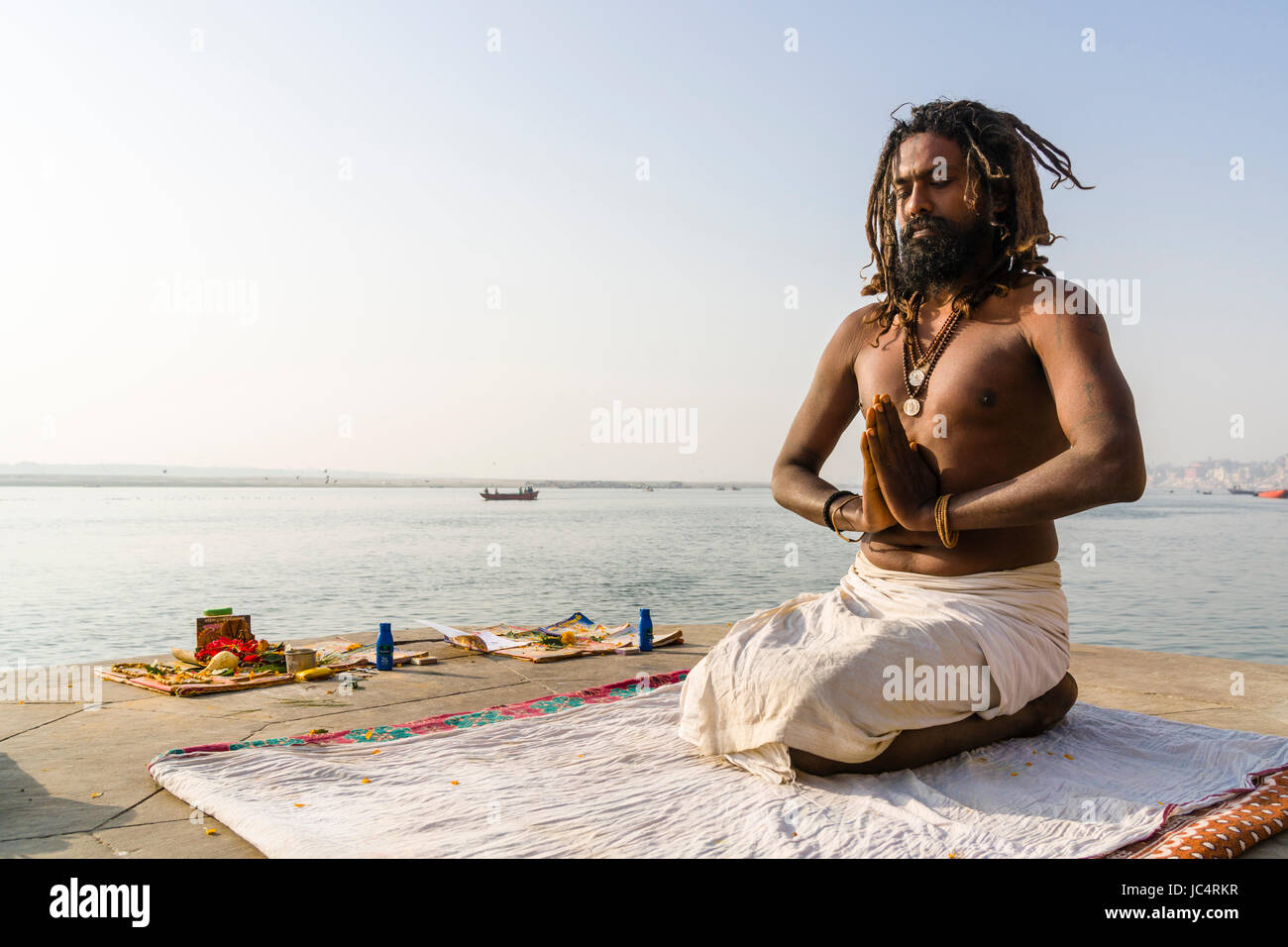 Un sadhu, uomo santo, è seduto e pregando su una piattaforma presso il fiume sacro Gange a meer ghat nel sobborgo godowlia Foto Stock