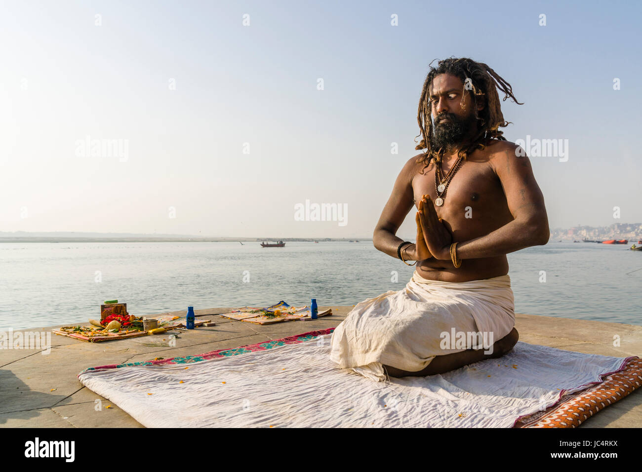 Un sadhu, uomo santo, è seduto e pregando su una piattaforma presso il fiume sacro Gange a meer ghat nel sobborgo godowlia Foto Stock