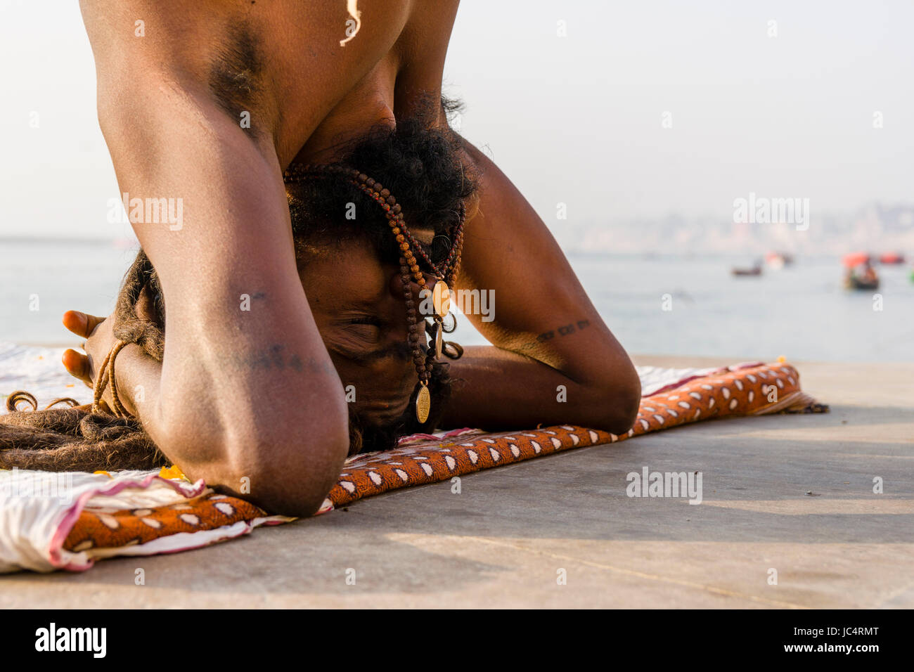 Un sadhu, uomo santo, è la pratica dello Yoga asana su una piattaforma presso il fiume sacro Gange a meer ghat nel sobborgo godowlia Foto Stock