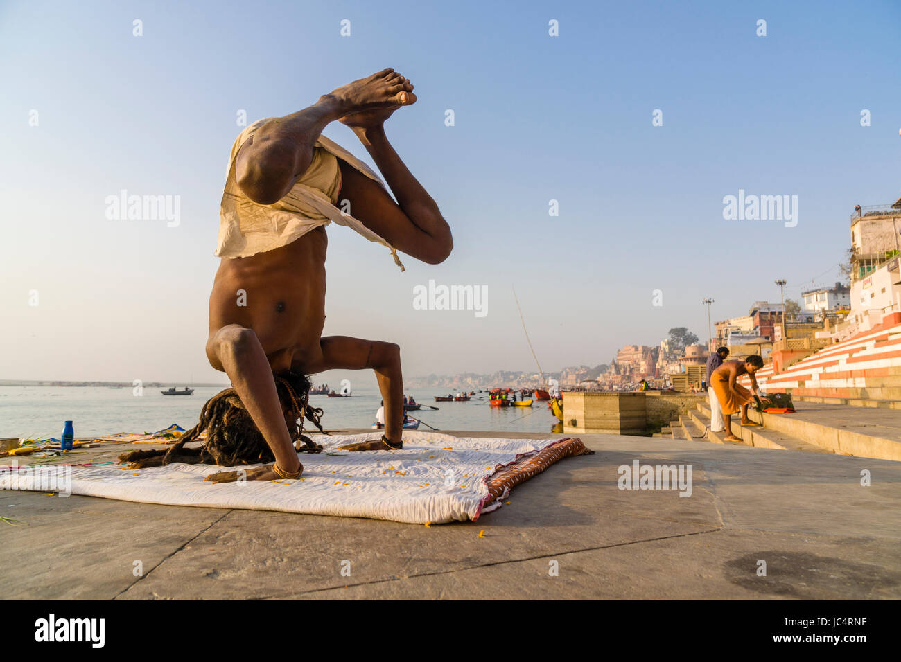 Un sadhu, uomo santo, è la pratica dello Yoga asana su una piattaforma presso il fiume sacro Gange a meer ghat nel sobborgo godowlia Foto Stock