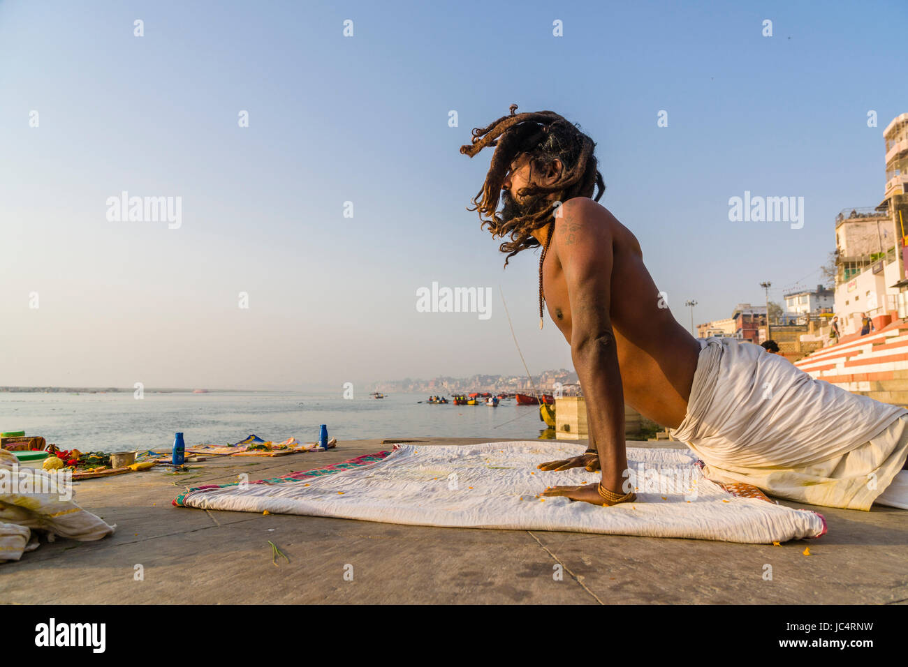 Un sadhu, uomo santo, è la pratica dello Yoga asana su una piattaforma presso il fiume sacro Gange a meer ghat nel sobborgo godowlia Foto Stock