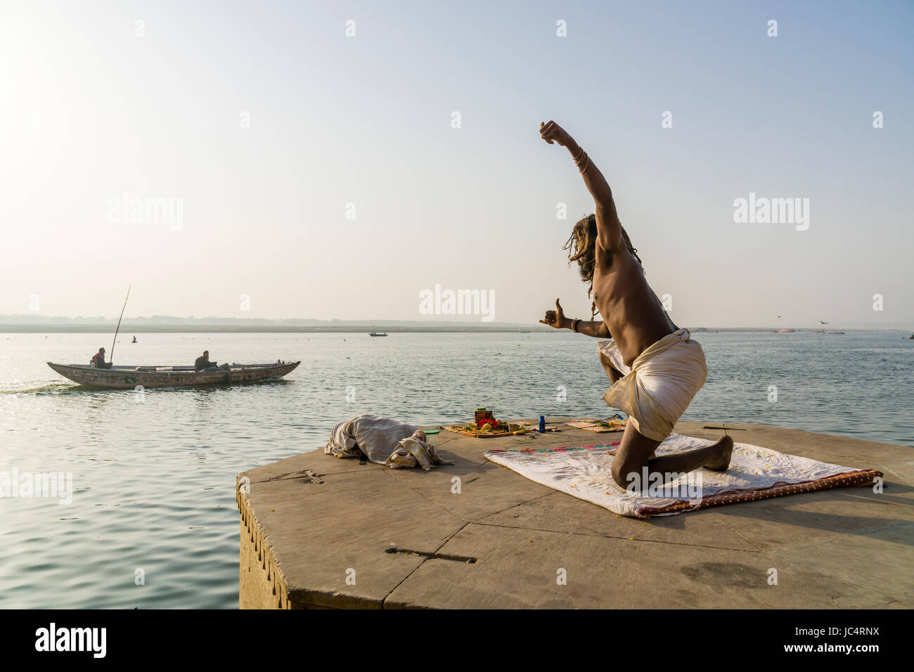 Un sadhu, uomo santo, è la pratica dello Yoga asana su una piattaforma presso il fiume sacro Gange a meer ghat nel sobborgo godowlia Foto Stock