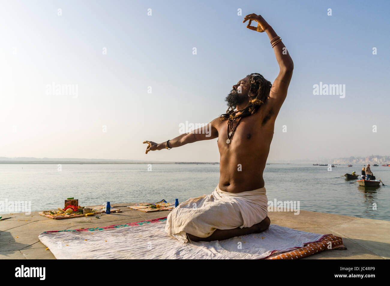 Un sadhu, uomo santo, è la pratica dello Yoga asana su una piattaforma presso il fiume sacro Gange a meer ghat nel sobborgo godowlia Foto Stock