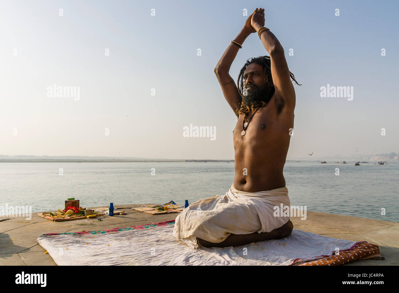 Un sadhu, uomo santo, è la pratica dello Yoga asana su una piattaforma presso il fiume sacro Gange a meer ghat nel sobborgo godowlia Foto Stock