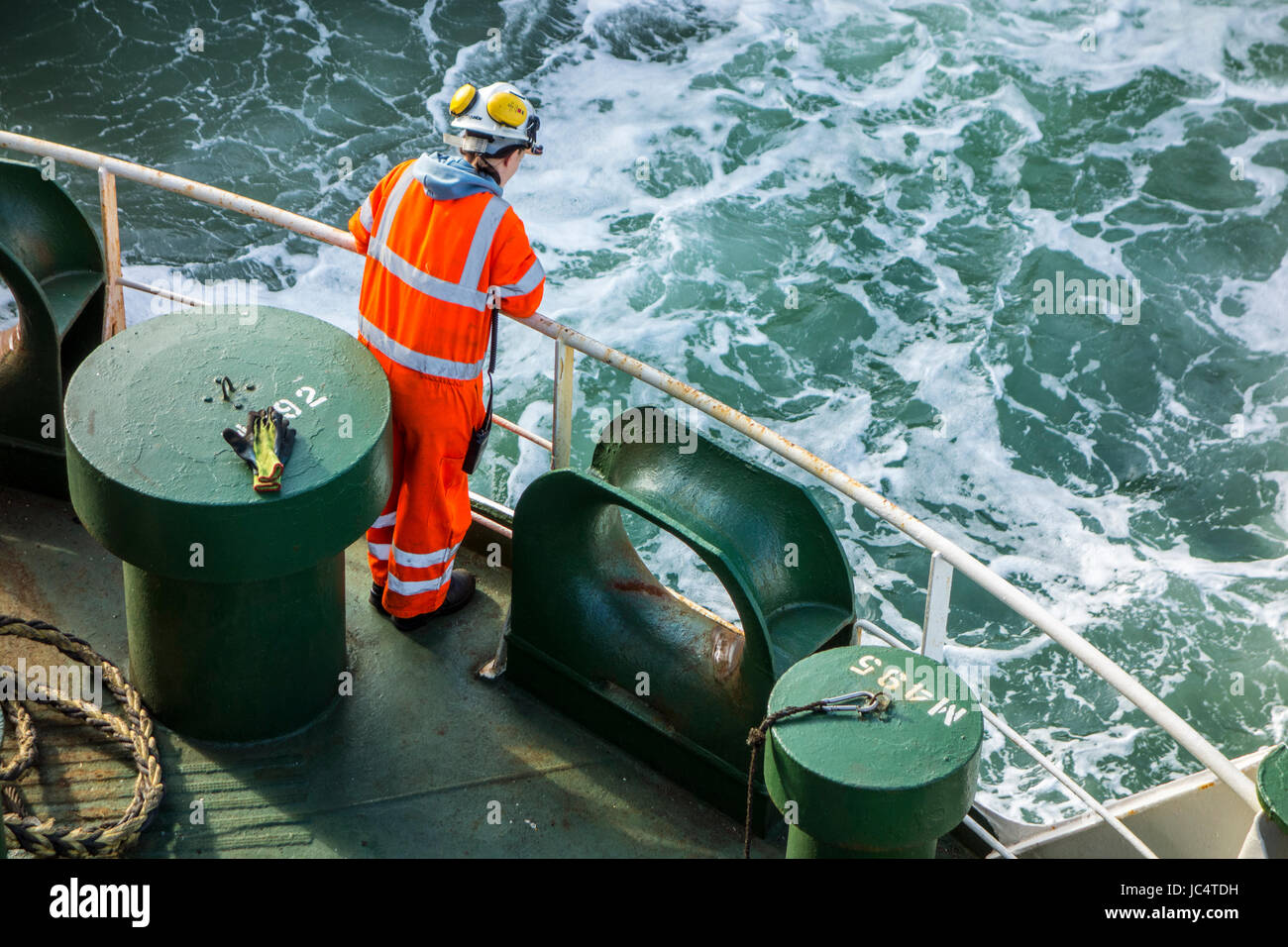 Femmina membro di equipaggio in arancione in generale e di indossare il casco di sicurezza lavorando sul ponte di car carrier / Nave cargo in mare Foto Stock