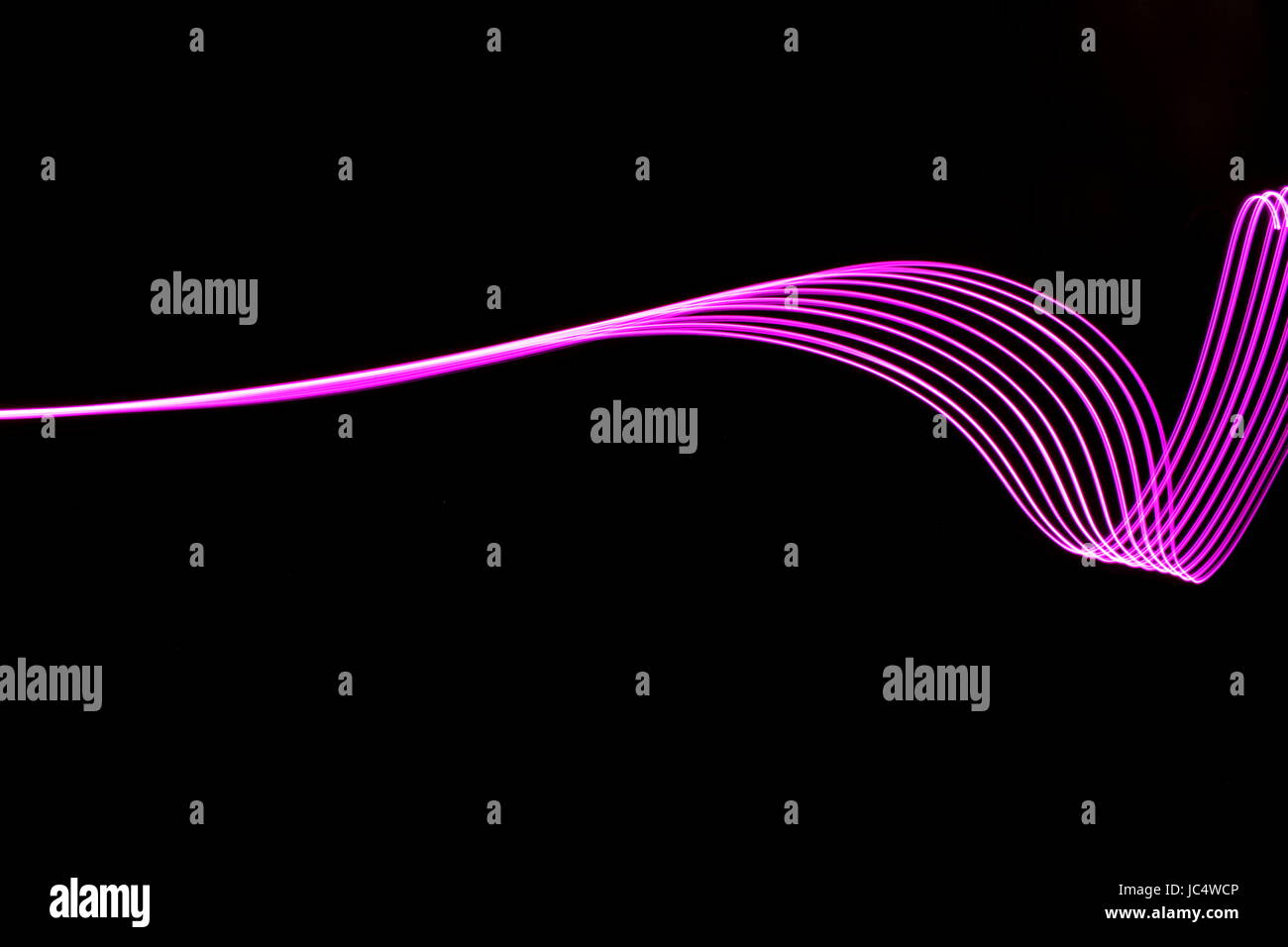 Luce rosa fotografia pittura, movimento fluido, volute e linee parallele patterns contro uno sfondo nero Foto Stock