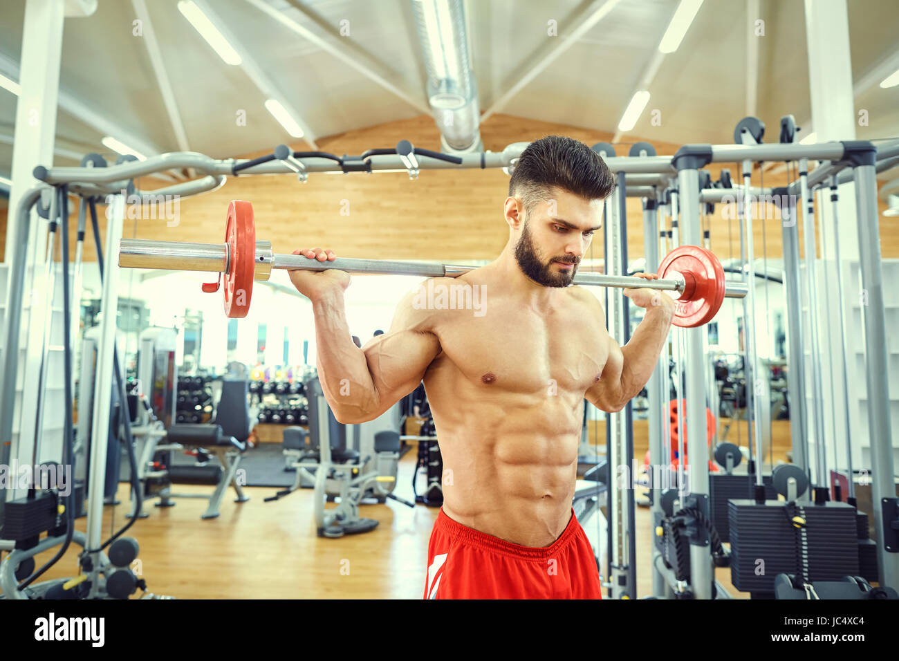 Culturista con un bar barbell fa esercizi in palestra Foto Stock