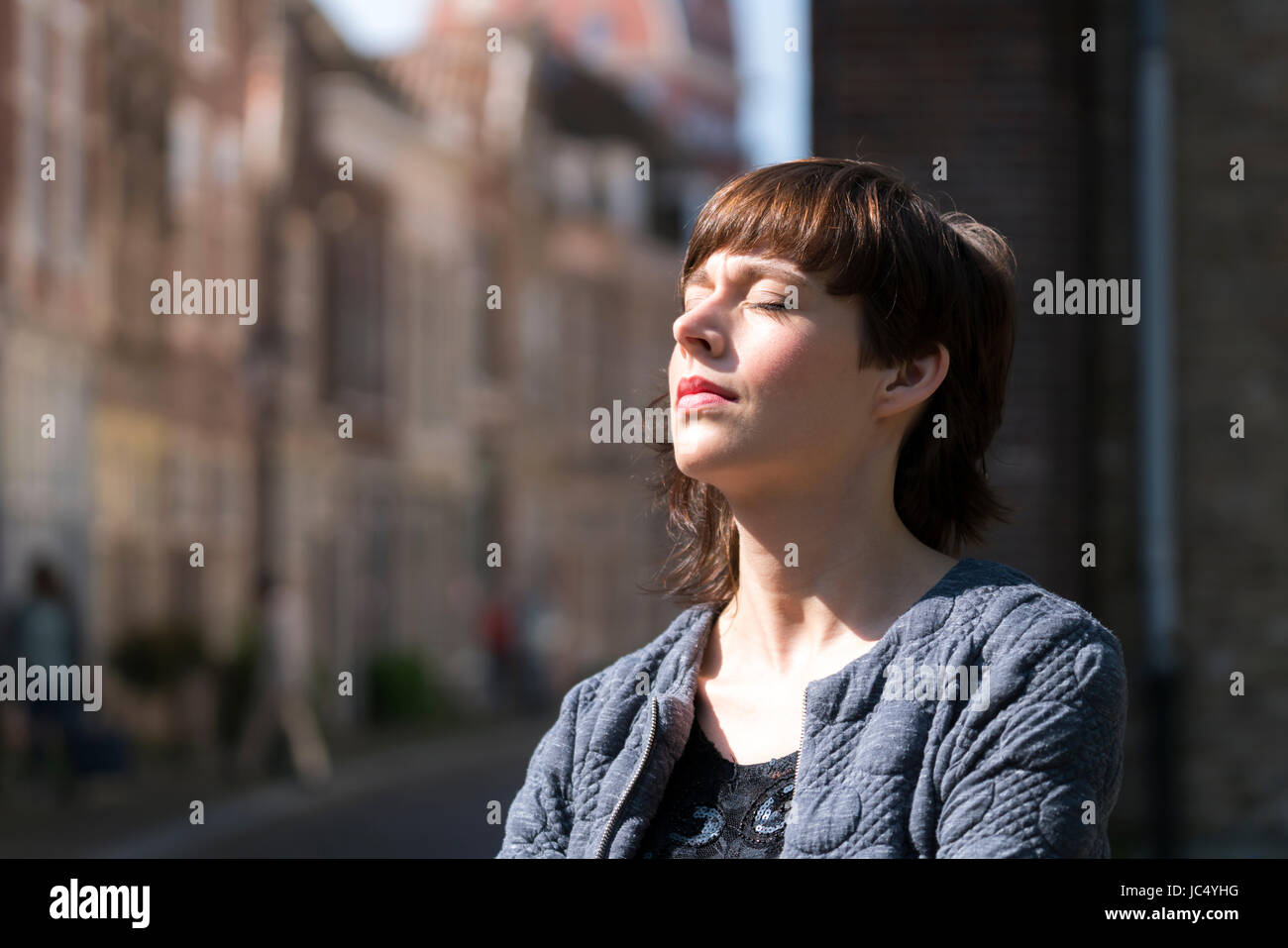 Bella giovane donna godendo il sole all'aperto nella città Foto Stock
