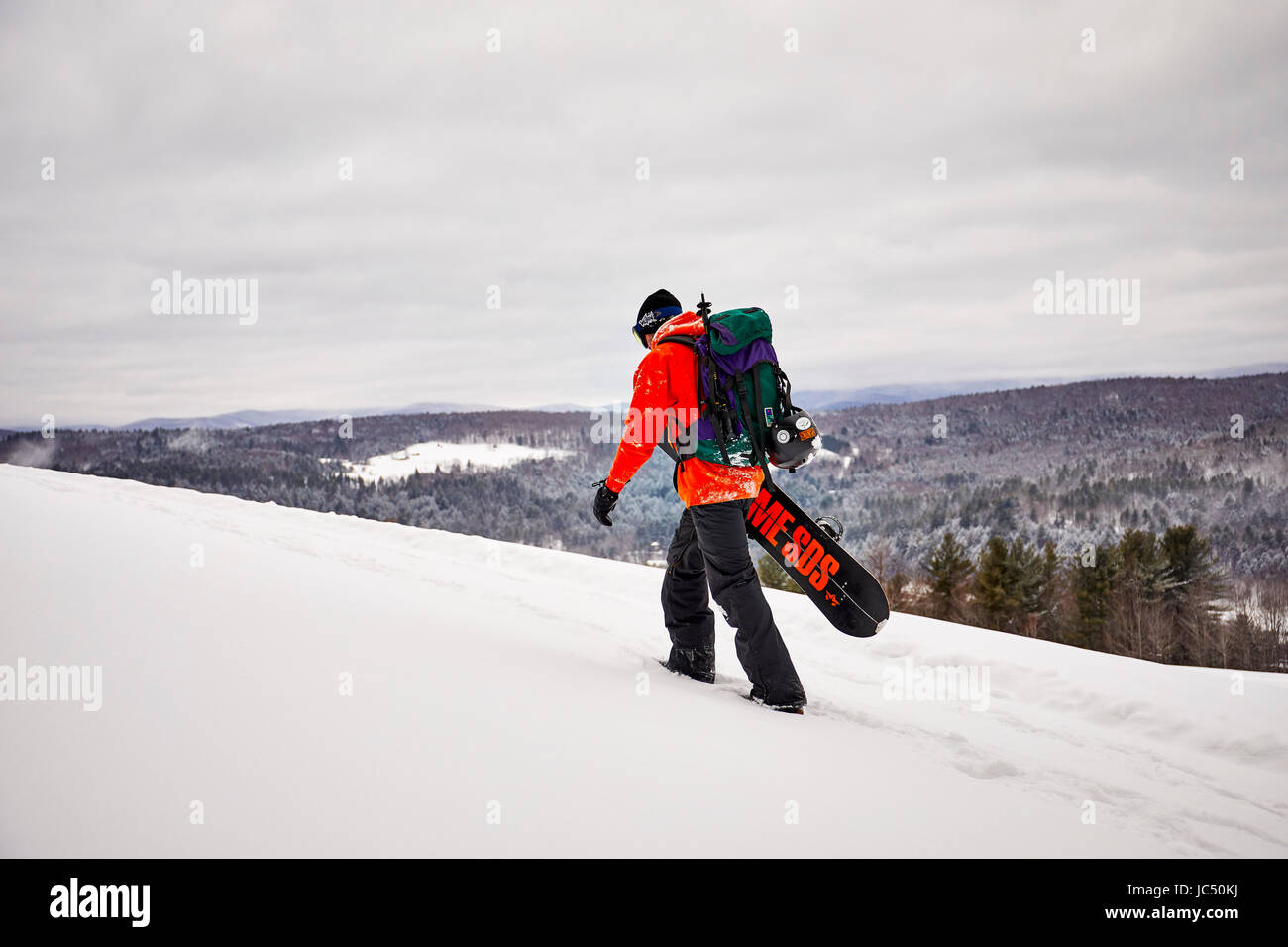 Un backcountry snowboarder escursionismo una cresta in Vermont. Foto Stock