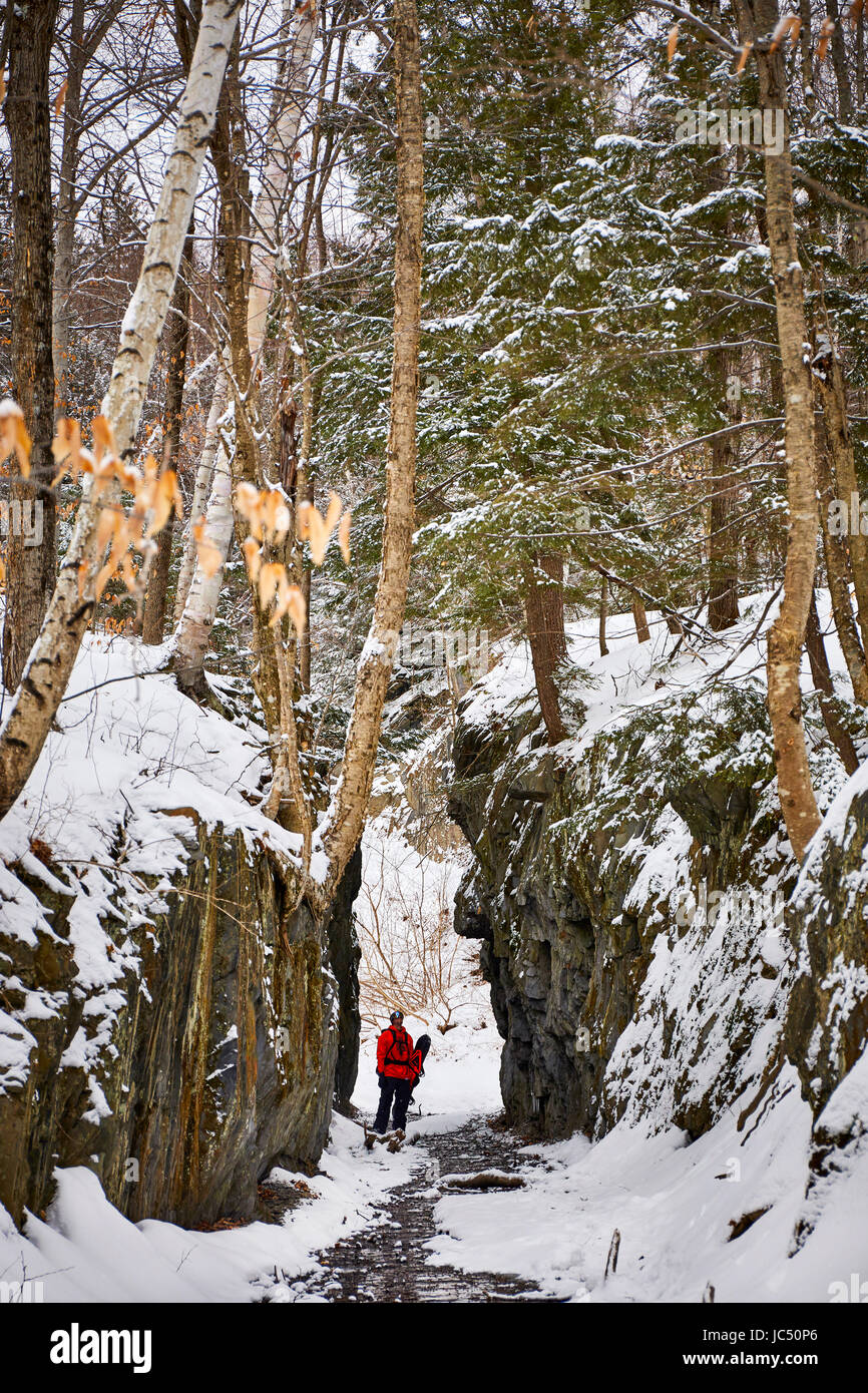 Uno snowboarder esplora l'entrata di una vecchia cava di Vermont. Foto Stock