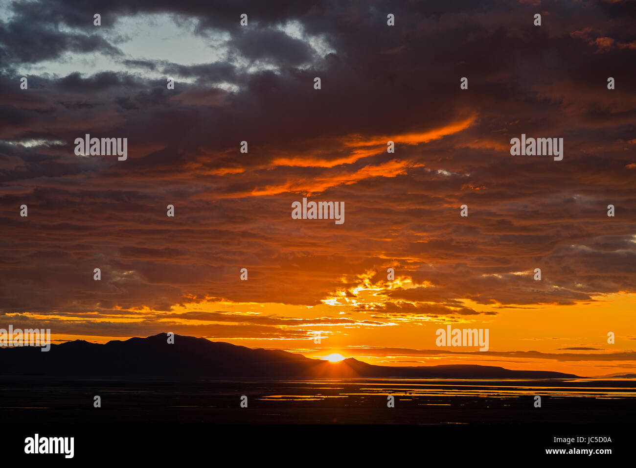 In questa foto il sole illumina il fondo delle nuvole come si imposta su Antelope Island. Antelope Island è la più grande isola del Grande Lago Salato Foto Stock