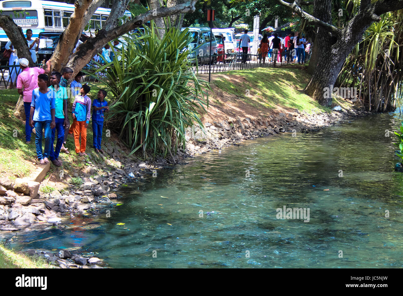 Un gruppo di giovani maschi in piedi accanto al lago di Kandy Sri Lanka sul giorno di poya Foto Stock