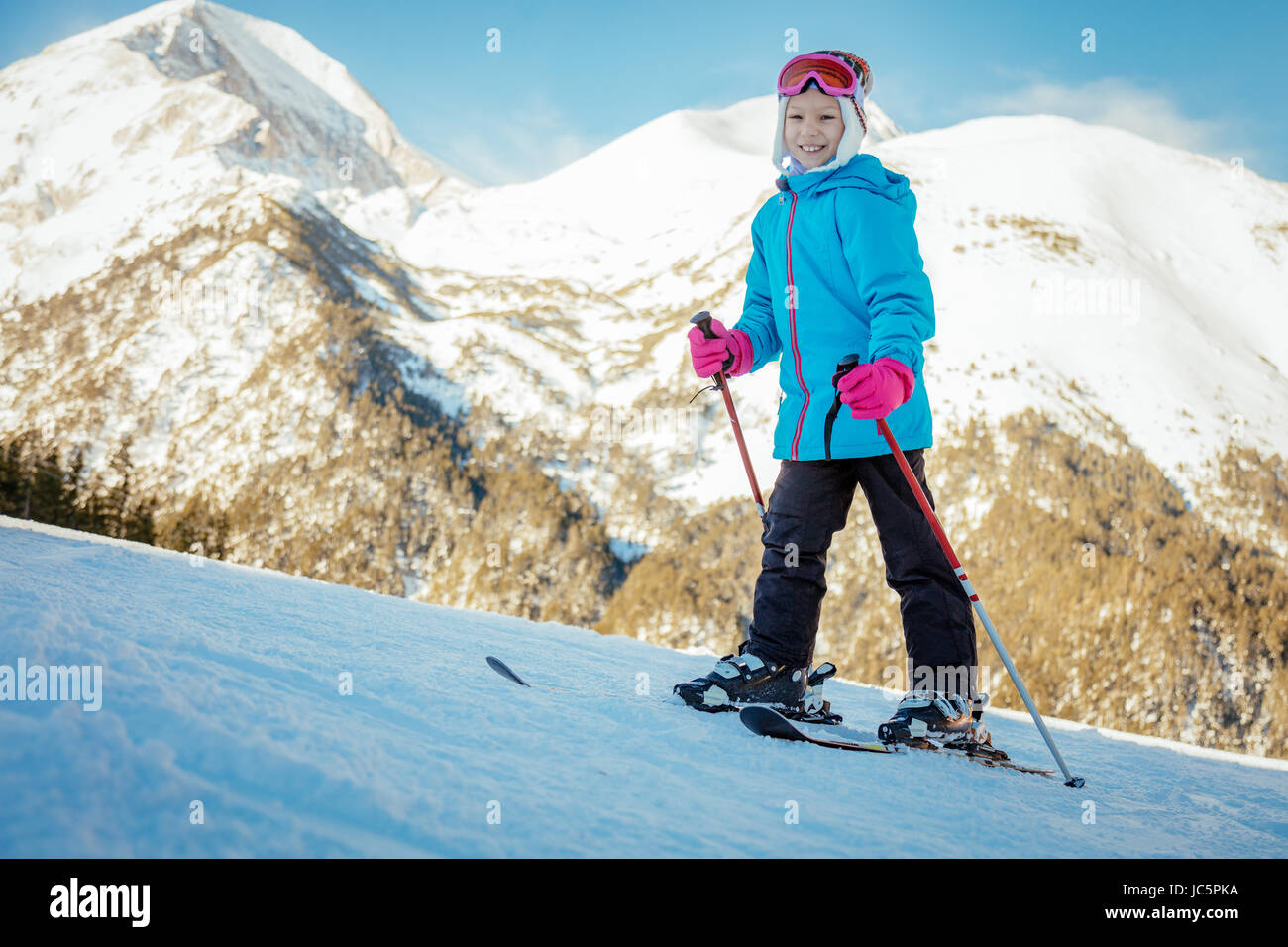 Carino sorridente bambina su sci godendo di una soleggiata giornata invernale. Foto Stock