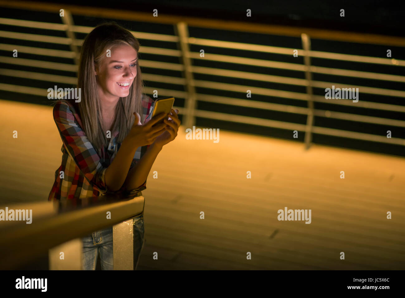 Una buona notizia. Bellissima fanciulla controlli qualcosa sul suo smart phone e sorrisi distrattamente. Foto Stock