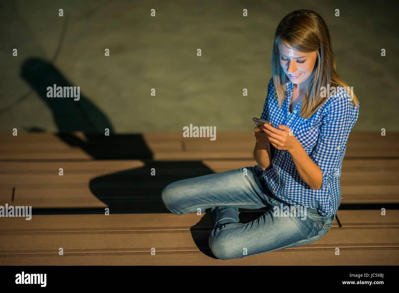 Una buona notizia. Bellissima fanciulla controlli qualcosa sul suo smart phone e sorrisi distrattamente. Foto Stock