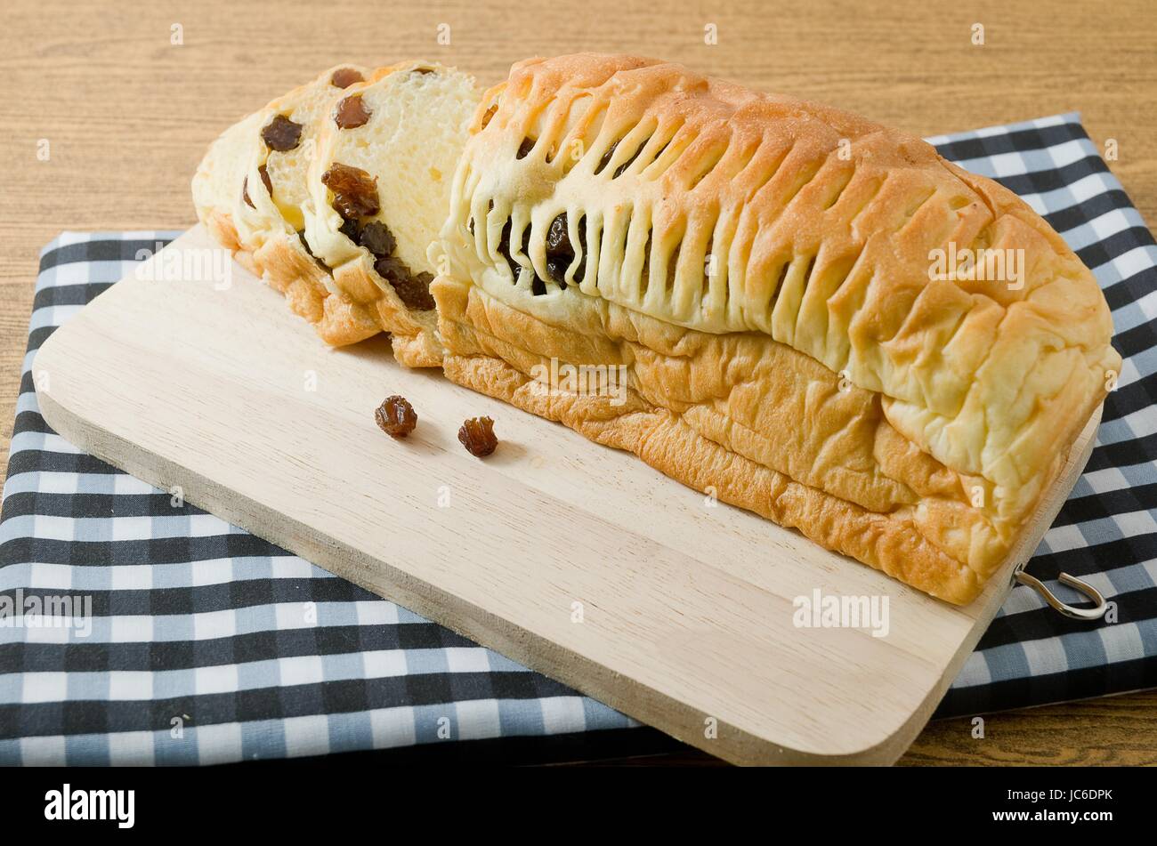 La cucina e il cibo, una pagnotta fatta in casa di marrone Raisin pane sul tagliere di legno. Foto Stock
