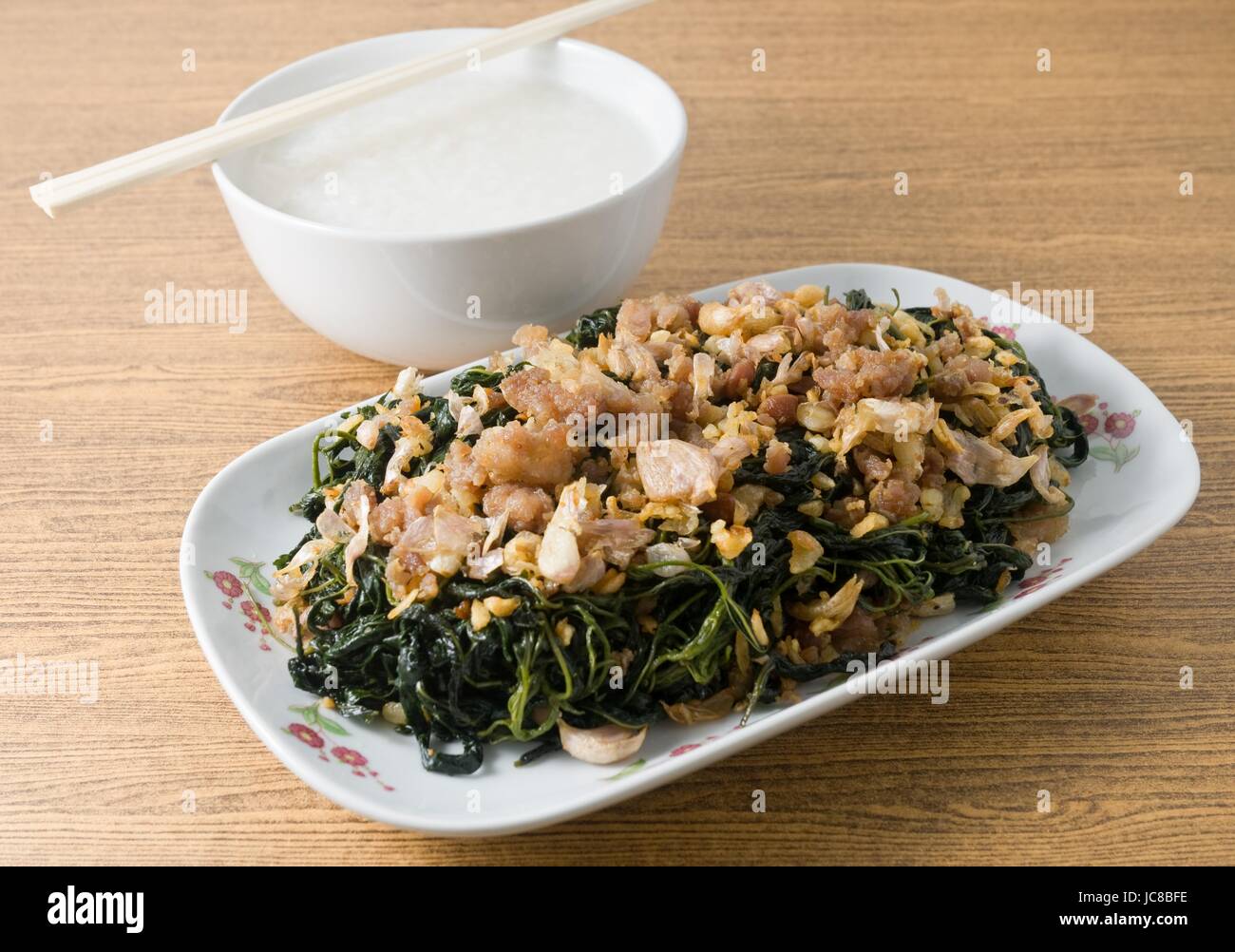 Cinese tradizionale cibo, saltate in padella Foglie di iuta o Mulukhiyah foglie con carne macinata di maiale, Garlics e fermentati di soia servito con farinata di riso. Foto Stock