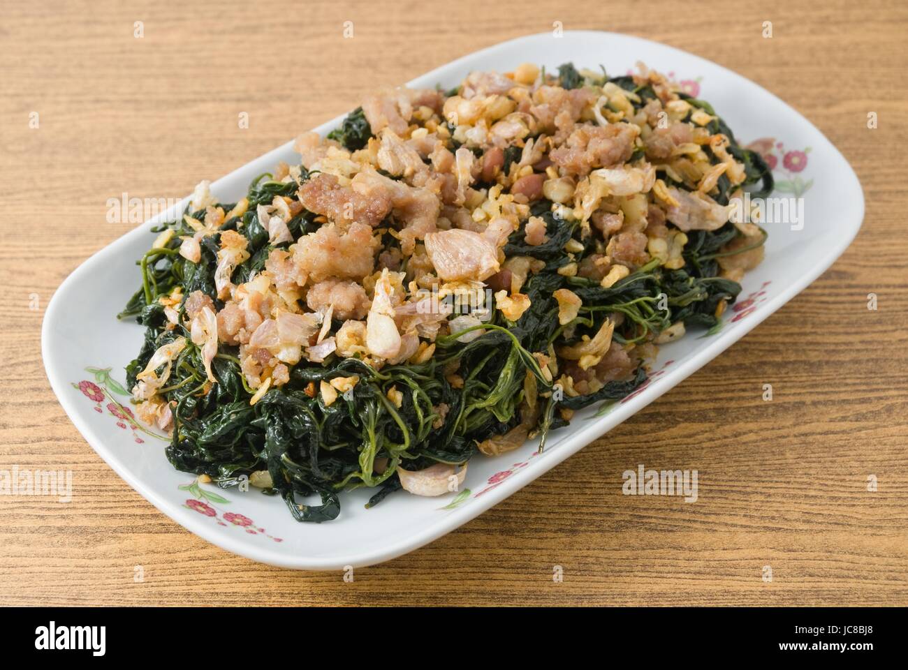 Cinese tradizionale cibo, una piastra di mescolare fritto di foglie di iuta o Mulukhiyah foglie con carne macinata di maiale, Garlics e fermentati di soia. Foto Stock