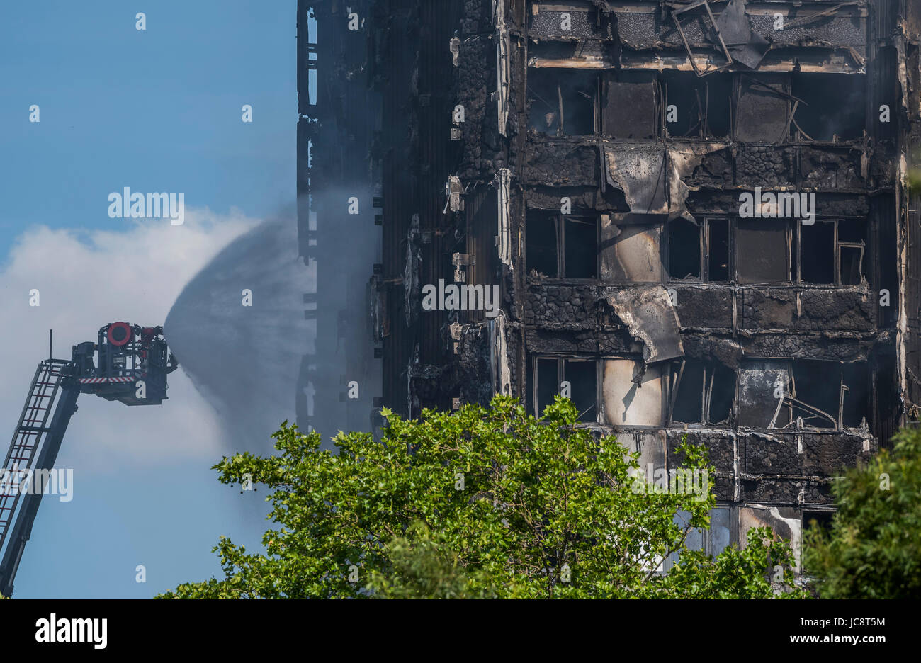 Londra, Regno Unito. 14 Giugno, 2017. Il servizio antincendio a getto di acqua tubi flessibili verso il basso la costruzione ma solo raggiunge circa a metà strada verso l'alto. Grenfell Tower - i resti carbonizzati della torre blocco che ha preso fuoco la scorsa notte in North Kensington vicino Latimer Road tube station. Londra 14 Giugno 2017. Credito: Guy Bell/Alamy Live News Foto Stock