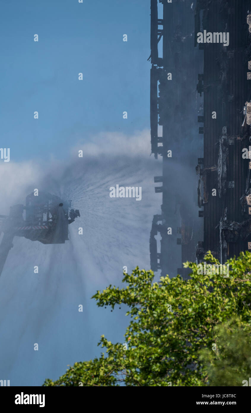 Londra, Regno Unito. 14 Giugno, 2017. Il servizio antincendio a getto di acqua tubi flessibili verso il basso la costruzione ma solo raggiunge circa a metà strada verso l'alto. Grenfell Tower - i resti carbonizzati della torre blocco che ha preso fuoco la scorsa notte in North Kensington vicino Latimer Road tube station. Londra 14 Giugno 2017. Credito: Guy Bell/Alamy Live News Foto Stock