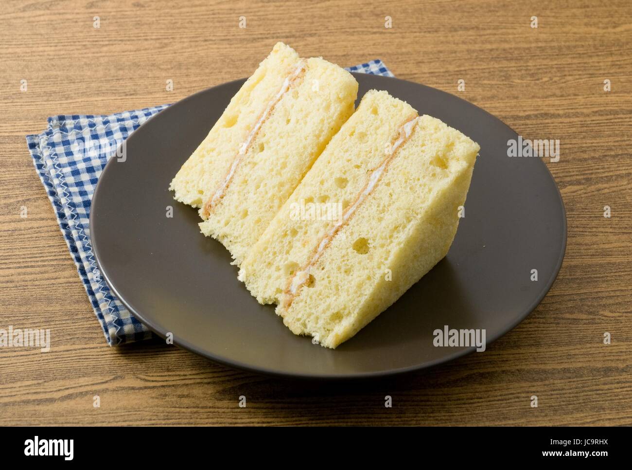 Snack e Dessert, Vaniglia Chiffon torta fatta con burro, uova, zucchero, farina, il lievito in polvere e aromi su un piatto nero. Foto Stock