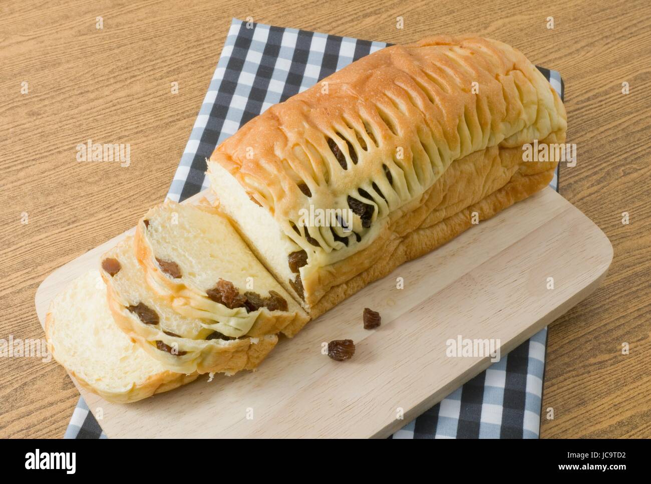 La cucina e il cibo in casa di una fetta di pane di marrone Raisin pane sul tagliere di legno. Foto Stock