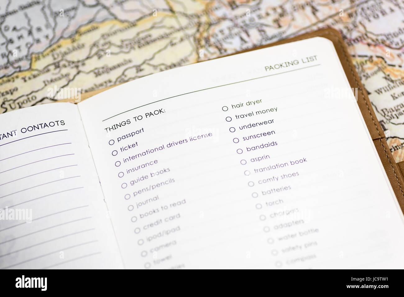 Primo piano di un diario di viaggio su una pagina di una distinta di imballaggio, con sfondo di una mappa d'epoca, incentrato su "cose da mettere in valigia", simboleggiando il concetto di viaggio Foto Stock