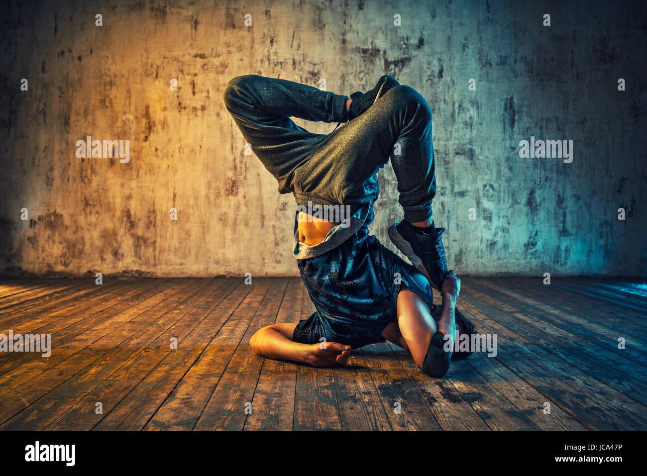 Giovane uomo break dancing sulla parete dello sfondo. Colori vibranti effetto. Foto Stock