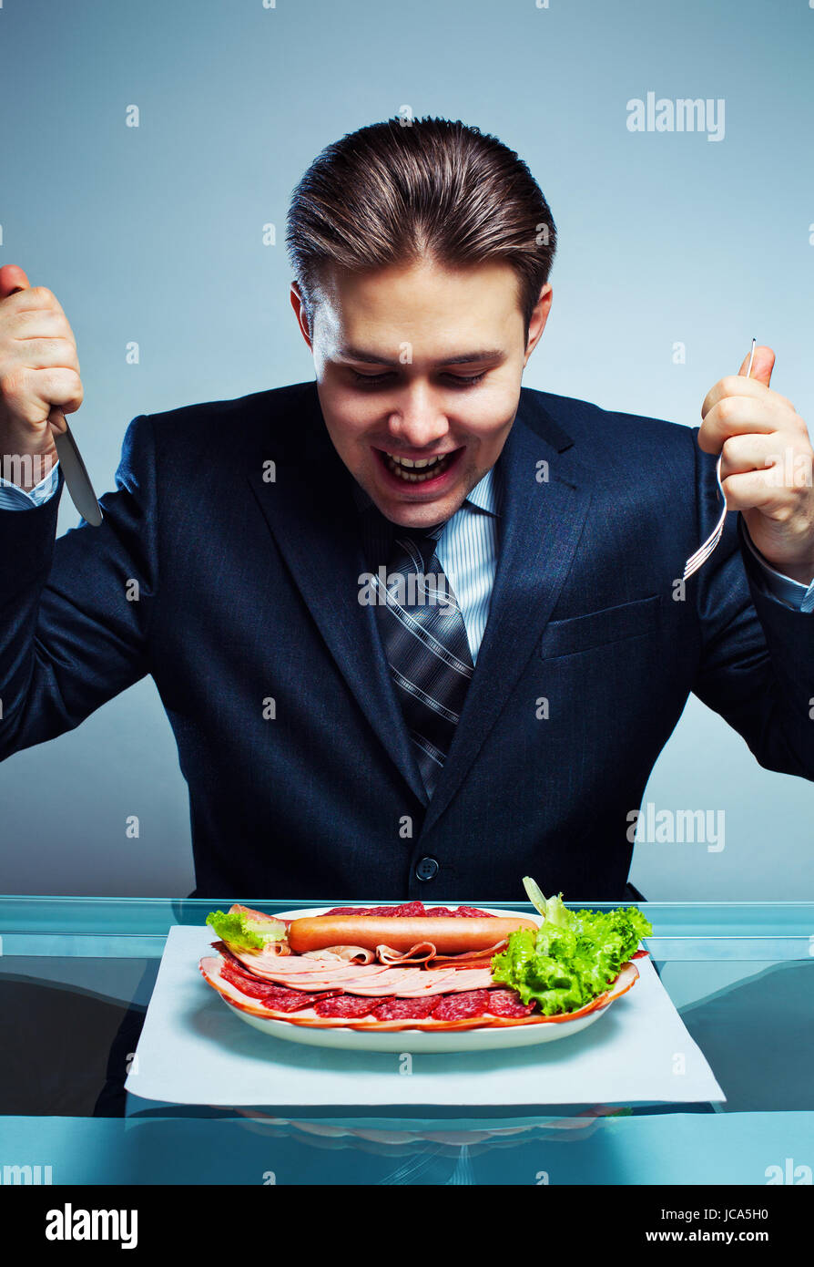Giovane imprenditore affamati correndo sulla piastra con ricchi menù a base di carne Foto Stock