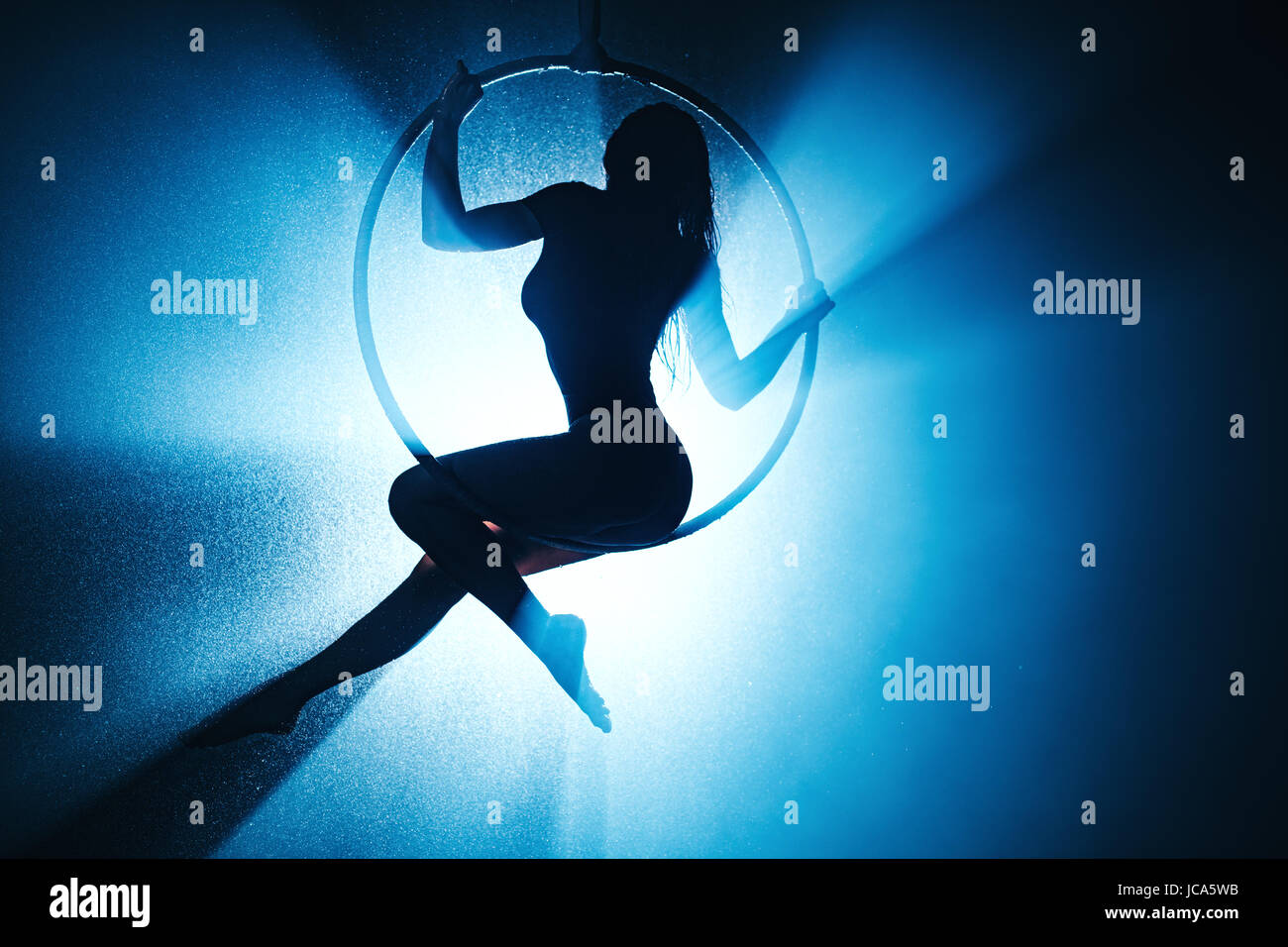 Sport Giovane donna silhouette sull'anello. Con acqua, fumo e la luce blu dal retro. Foto Stock