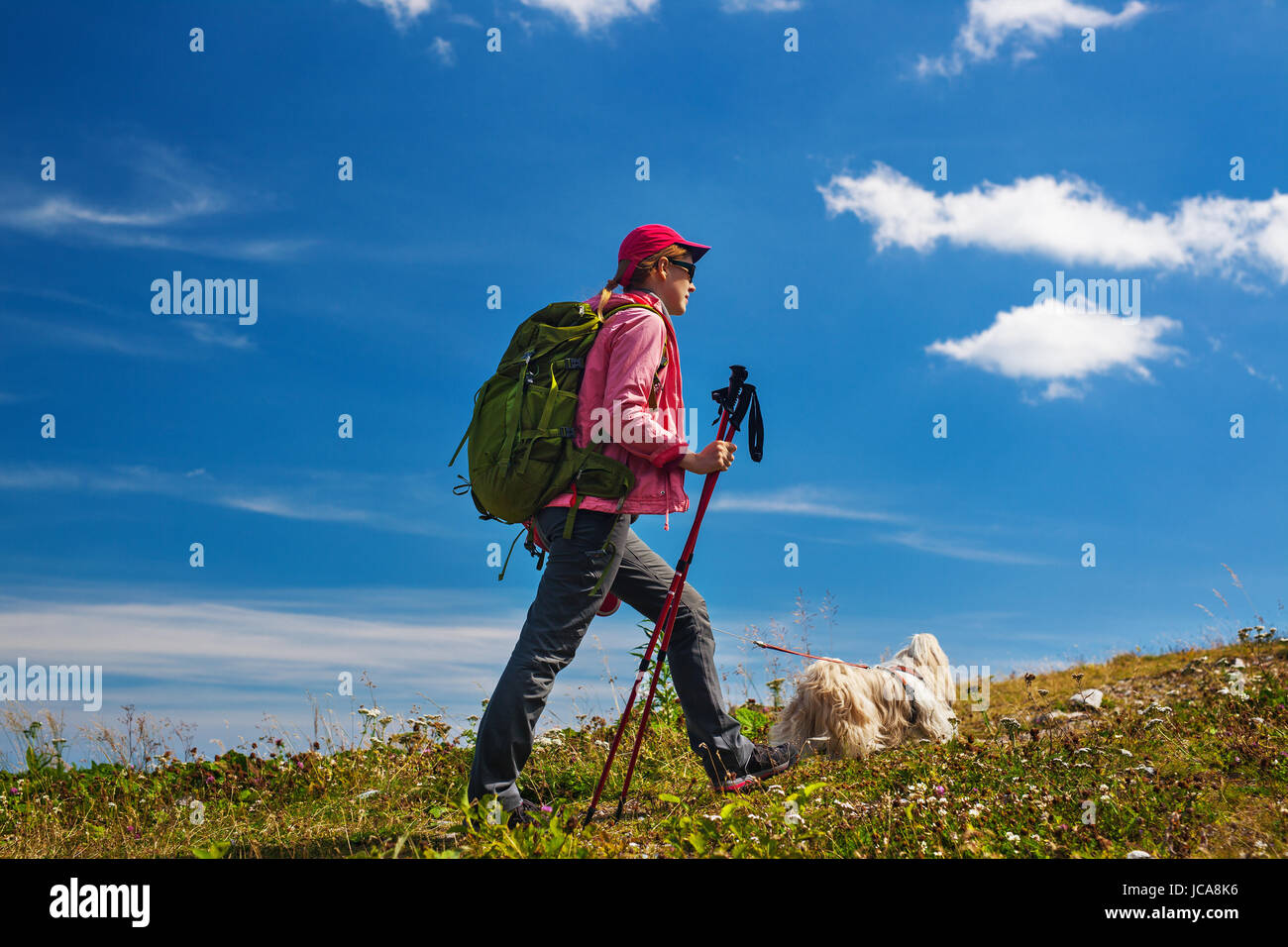 Giovane donna turistico con cane in viaggio per le montagne blu su sfondo cielo Foto Stock