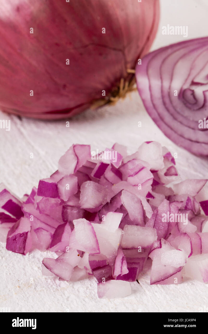 Rote Speise Zwiebel im ganzen und in kleinen Würfeln Brunoise in einer Schale auf einem weißen Holzbrett Foto Stock